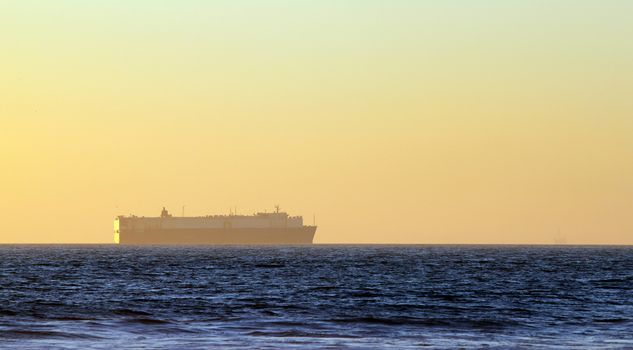 Large container freighter on the horizon during sunset.