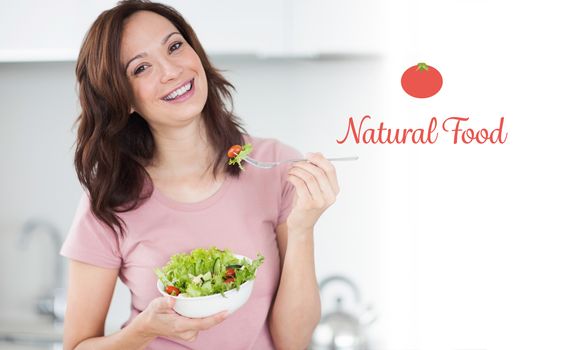 Natural food against portrait of smiling woman with a bowl of salad in kitchen