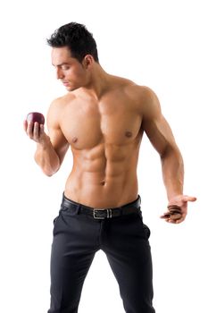 Muscular man deciding between healthy fruit and cookies