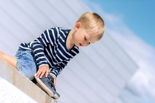 Portrait of little preschool boy outdoors with shoes