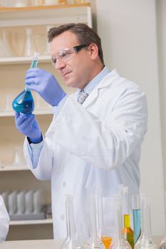 Scientist examining blue precipitate in baker 