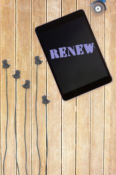 Renew against tablet and plugs on wooden background