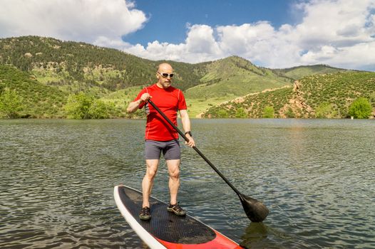 male paddler enjoying stand up paddling on a sunny summer day - Horsetooth Reservoir, Fort Collins, Colorado