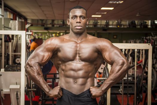 Handsome black male bodybuilder posing in gym