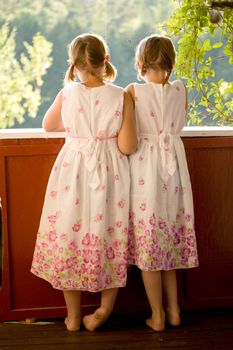 Twin girls on porch in summer dresses