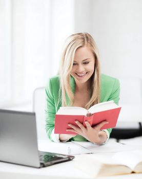 smiling student girl reading book in college