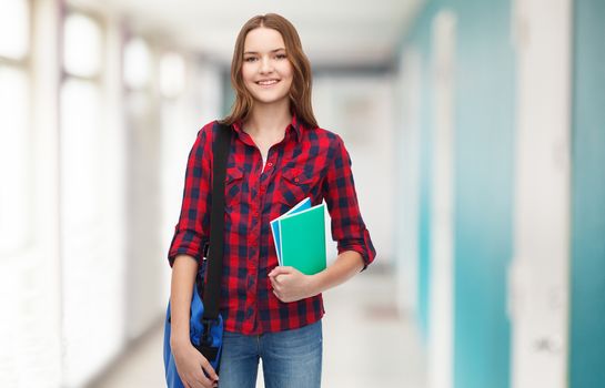 smiling female student with bag and notebooks