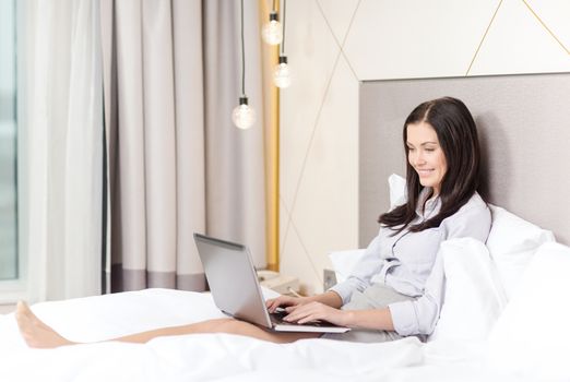 happy businesswoman with laptop in hotel room