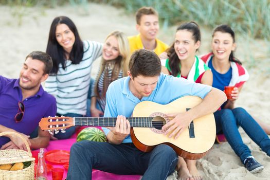 group of happy friends playing guitar on beach