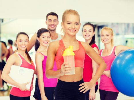 smiling sporty woman with protein shake bottle