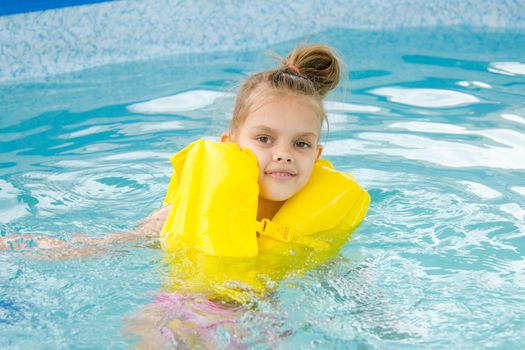 Girl swimming in the pool in the lifejacket