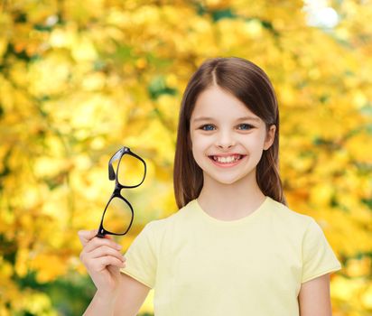 smiling cute little girl holding black eyeglasses