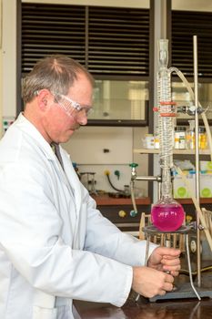 Chemist heating liquid in round-bottom flask