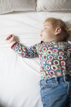 colored shirt baby sleeping on white bed