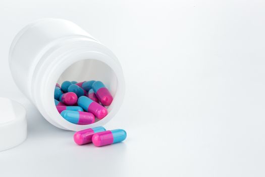 skyblue and pink pills an pill bottle on white background
