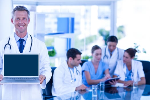 Doctor showing laptop with colleagues behind