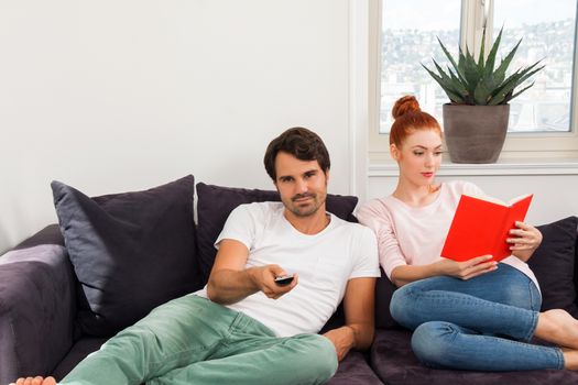 Sweet Couple Resting on Couch While Reading a Book