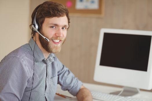 Bearded hipster at desk with headset in his office