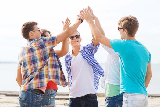 group of smiling friends making high five outdoors