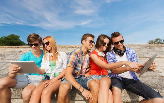 group of smiling friends with tablet pc outdoors