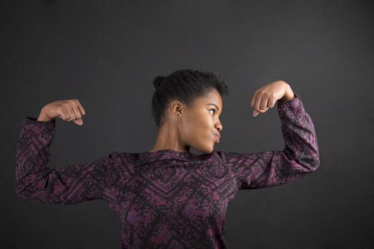 African woman with strong arms on blackboard background