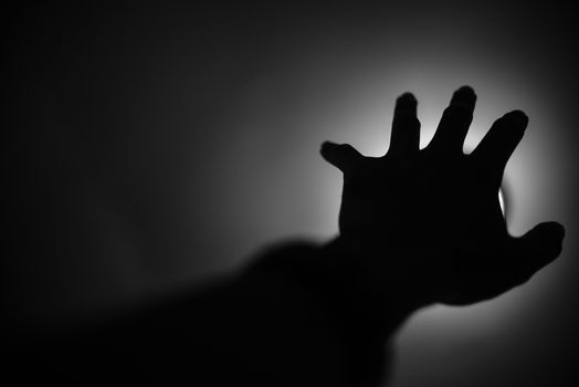 Silhouette of hand reaching to light, Help me concept