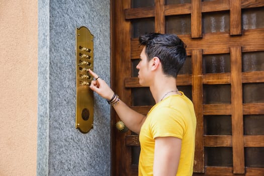 Young man ringing doorbell and talking on speaker phone
