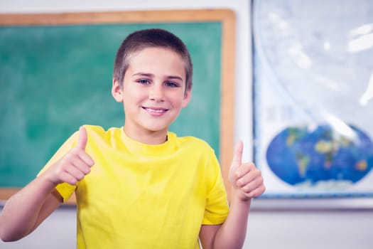 Smiling pupil doing thumbs up in a classroom