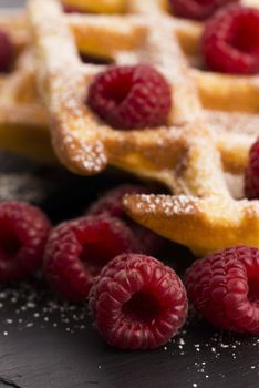 fresh waffles garnished with powdered sugar and raspberries 
