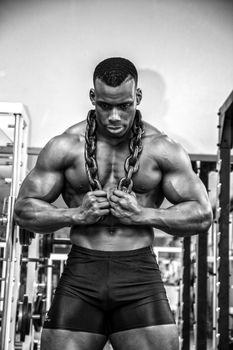 Attractive hunky black male bodybuilder posing with iron chains