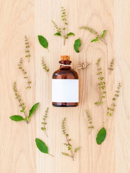 Bottle of essential oil with holy basil leaf and flower on woode