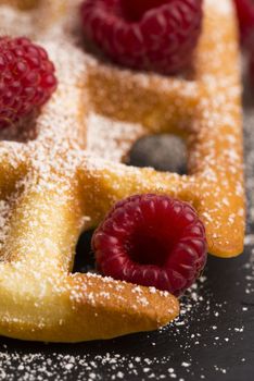 fresh waffles garnished with powdered sugar and raspberries 