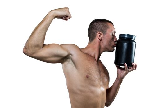 Athlete flexing muscles while kissing nutritional supplement container 