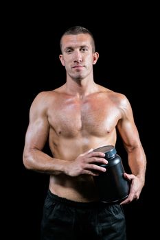 Portrait of handsome shirtless man holding nutritional supplement