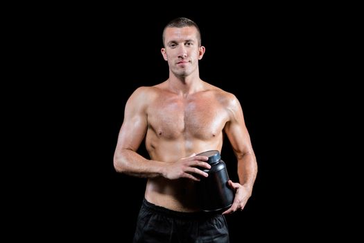 Confident shirtless man holding nutritional supplement
