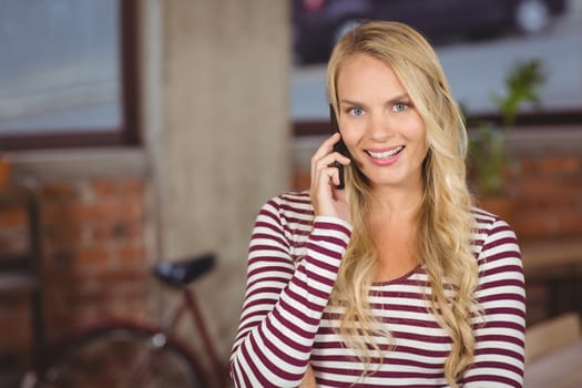 Portrait of happy businesswoman talking over phone in office