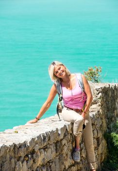 Young smiling blond sitting on stone wall