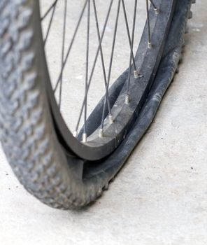 old Bicycle wheel with flat tyre on road