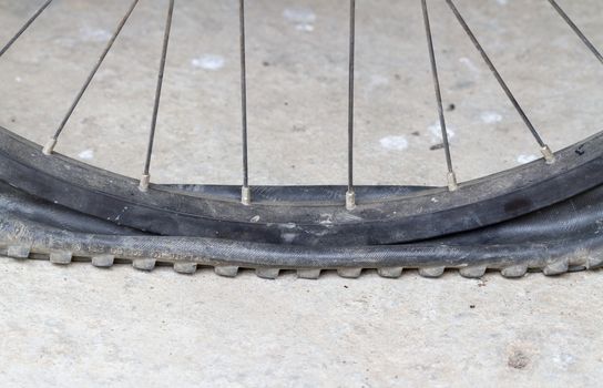 old Bicycle wheel with flat tyre on road