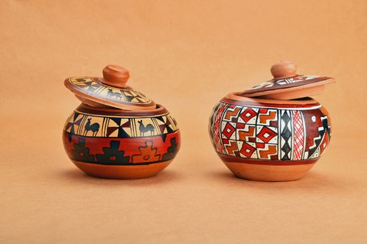 Two painted handmade ceramic pot with lids on kraft paper