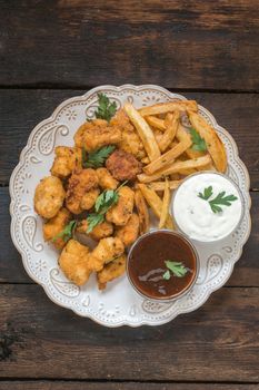Chicken nuggets and french fries in the plate on wooden background,from above 