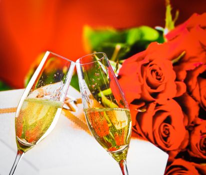 champagne flutes with golden bubbles on wedding roses flowers background