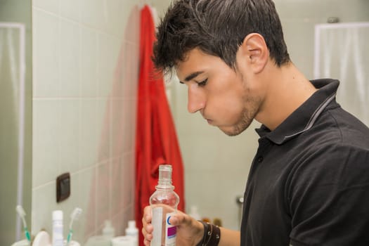 Young Man Rinsing with Mouth Wash in Bathroom