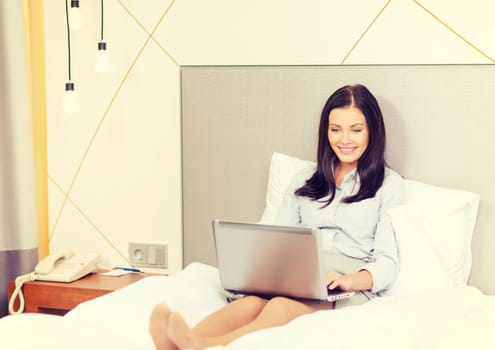 happy businesswoman with laptop in hotel room
