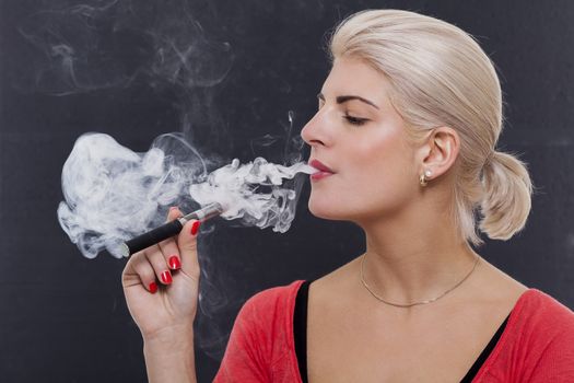 Stylish blond woman smoking an e-cigarette