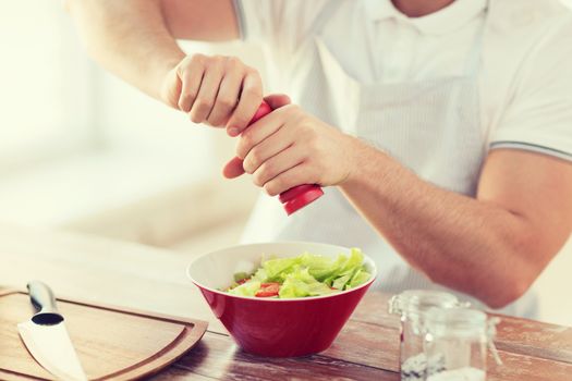 close up of male hands flavouring salad in a bowl