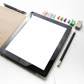 tablet with office supplies over white table
