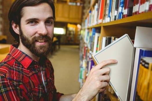 Happy student picking book in library