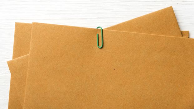 brown paper with green paper clip over white table