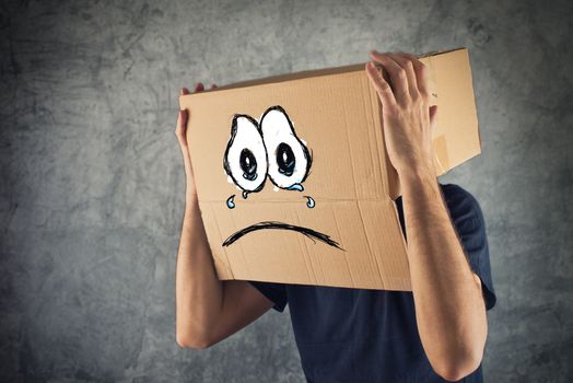 Man with cardboard box on his head and sad face expression